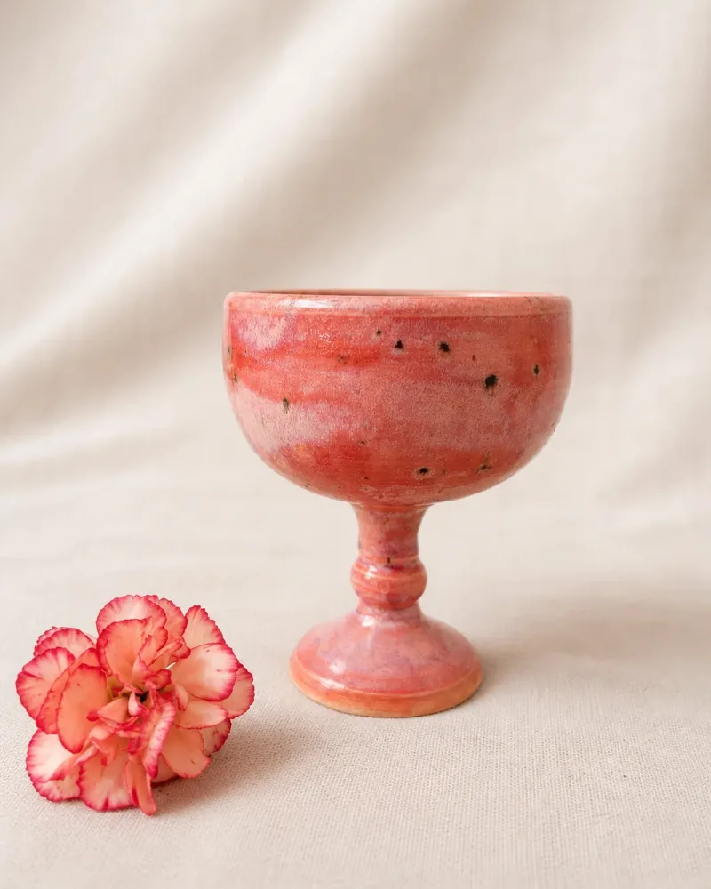 Dragon Fruit goblet, rose speckled glaze, beside a striped carnation on linen